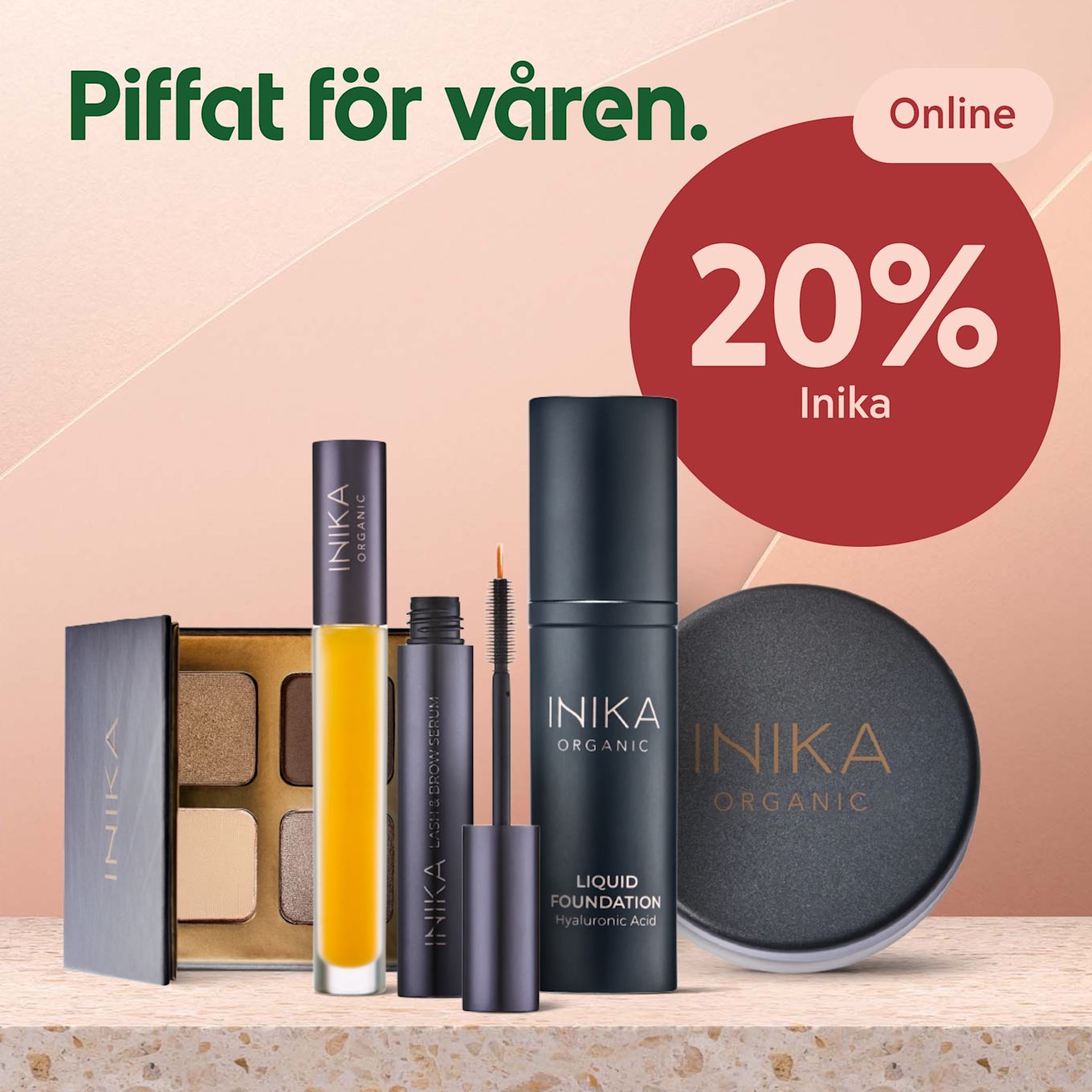 Rosatonad bakgrund med fem Inika Organic-sminkprodukter i förgrunden: ögonskuggspalett, gul läpp- eller oljeflaska, öppnad mascara med borste, flytande foundationflaska och rund puderburk, samt rött cirkelmärke med texten "20% Inika".