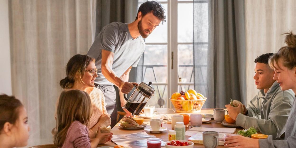 En familj sitter runt matbordet och äter frukost. Kosttillskott står på bordet.