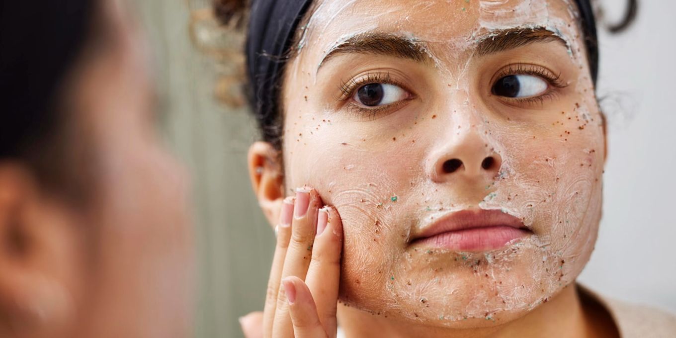 Person applicerar peeling i ansiktet. Bilden illustrerar en hudvårdsrutin för hösten med fokus på rengöring och återfuktning.
