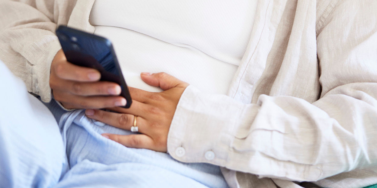 En kvinna med handen vilande på den nedre delen av magen. 