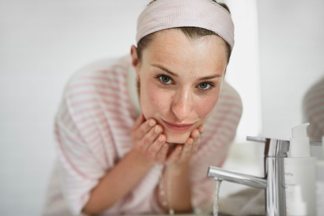 Tjej tvättar ansiktet i badrummet.