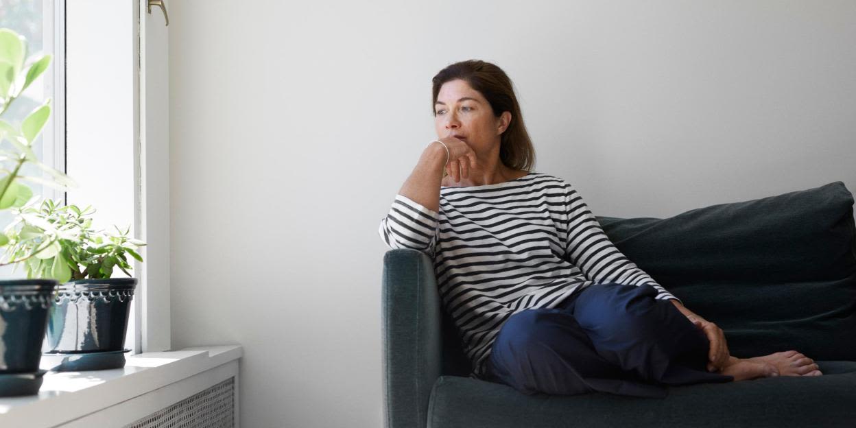 Kvinna sitter på en soffa och ser bekymrad ut.
