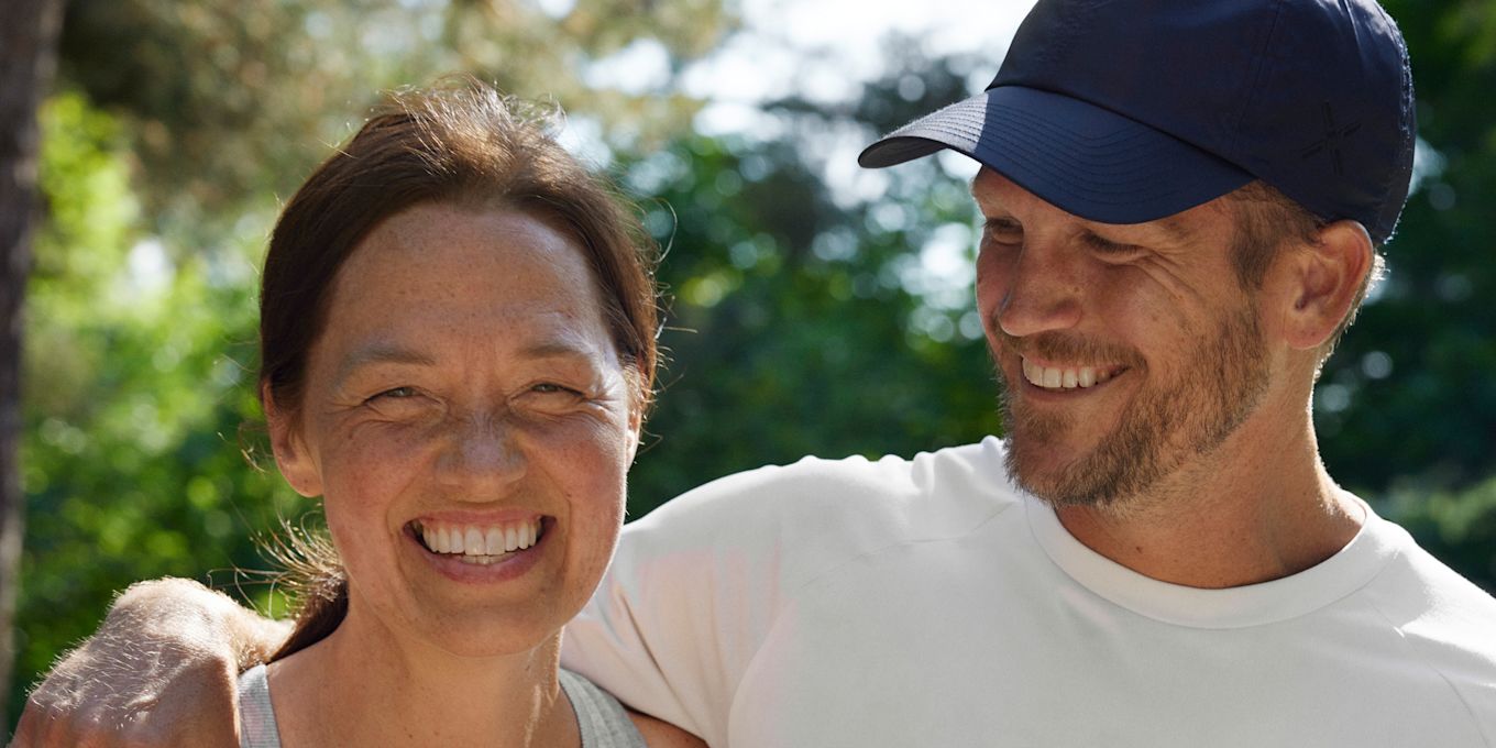 Glad kvinna och man är ute i sommarsolen. Mannen håller om kvinnan om axeln och tittar på henne.