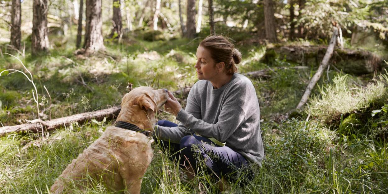 Kvinna och en hund i skogen.
