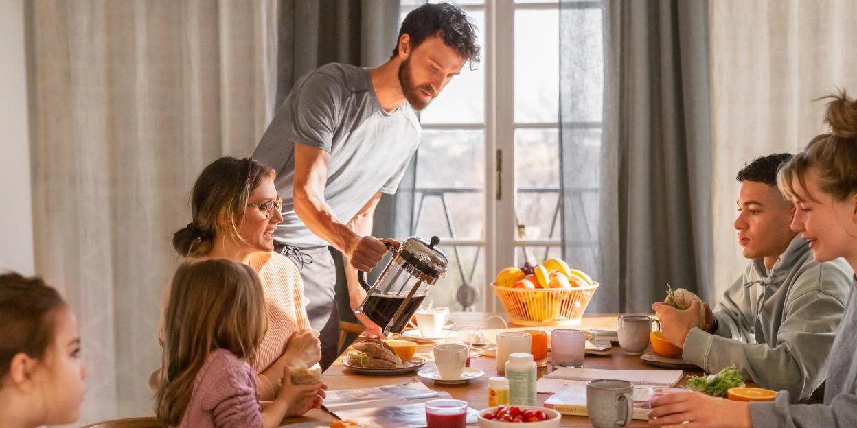 Familj äter vid frukostbordet en solig morgon.