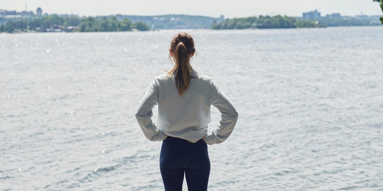 Kvinna står och blickar ut över vattnet.