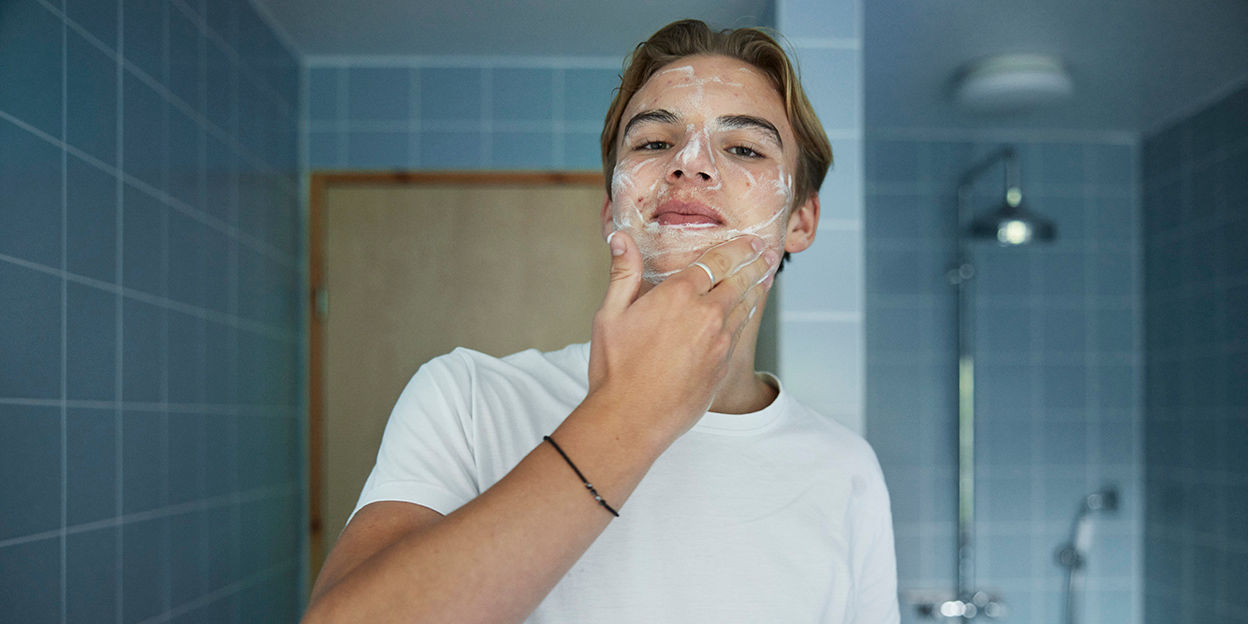 Ung kille rengör ansiktet i badrummet. 