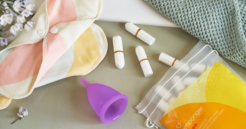 På ett bord ligger en påse med tamponger från Apotek Hjärtat, en menskopp och en tygbinda.