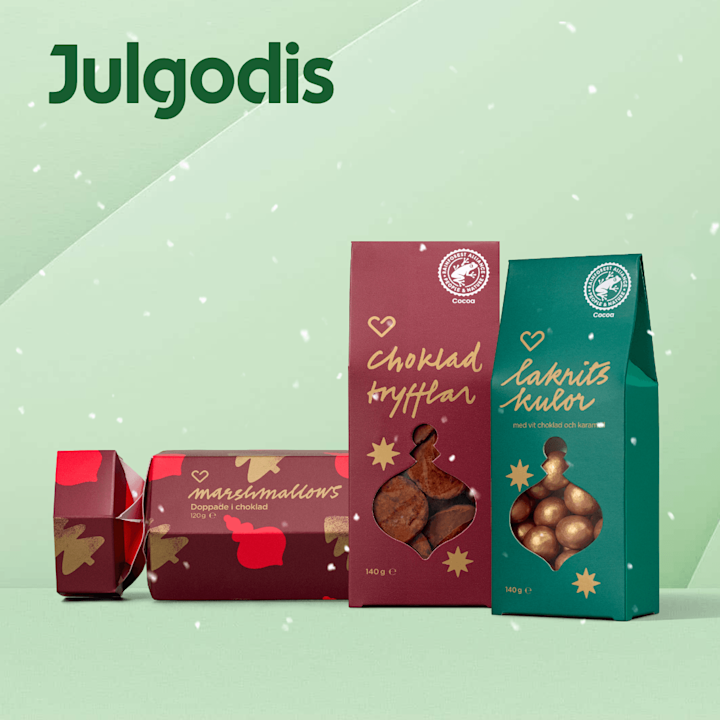 Julgodisförpackningar i rött och grönt på mintgrön bakgrund, tre paket märkta "marshmallows", "chokladtryfflar" och "lakritskulor" med genomskinliga fönster som visar bollar och tryfflar, snöflingor i förgrunden.