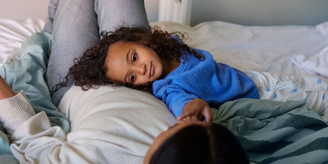 Mamma och dotter ligger i sängen och kollar på varandra.