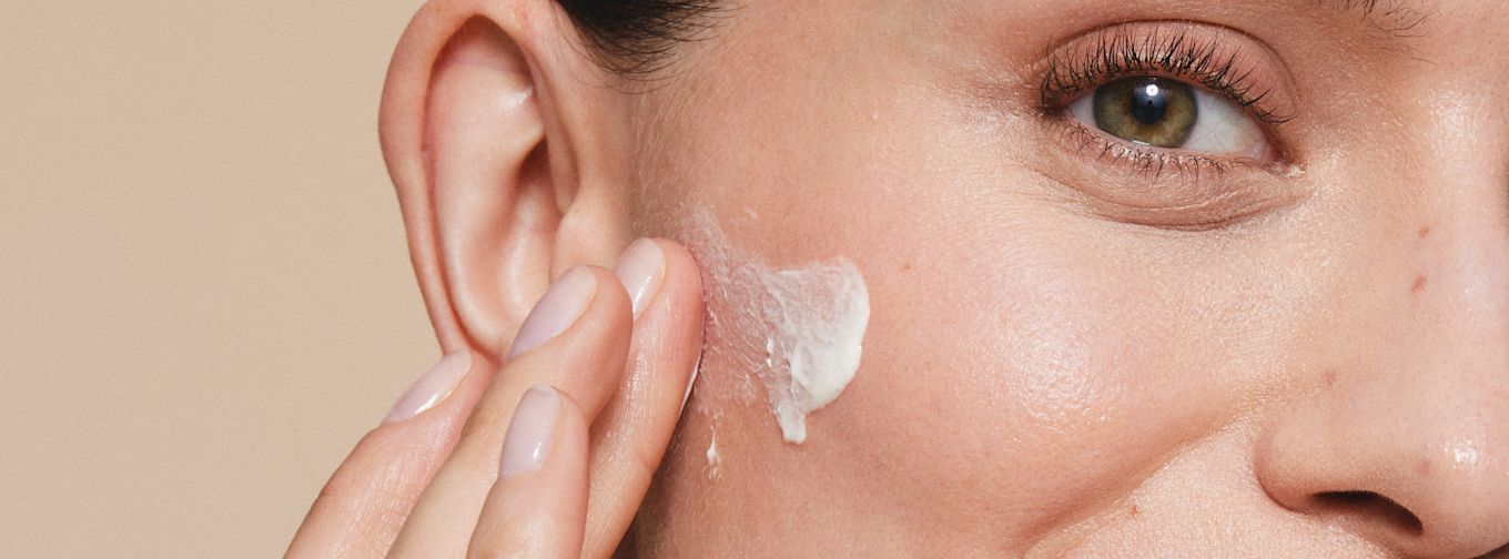 Kvinna smörjer in kinden med ansiktskräm.