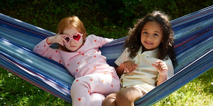 Två barn som ligger i hängmattan en solig dag.
