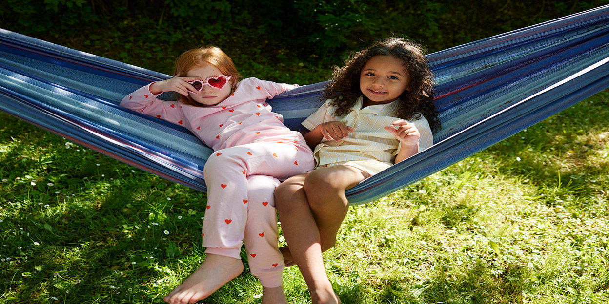 Två barn i en hängmatta en solig sommardag.