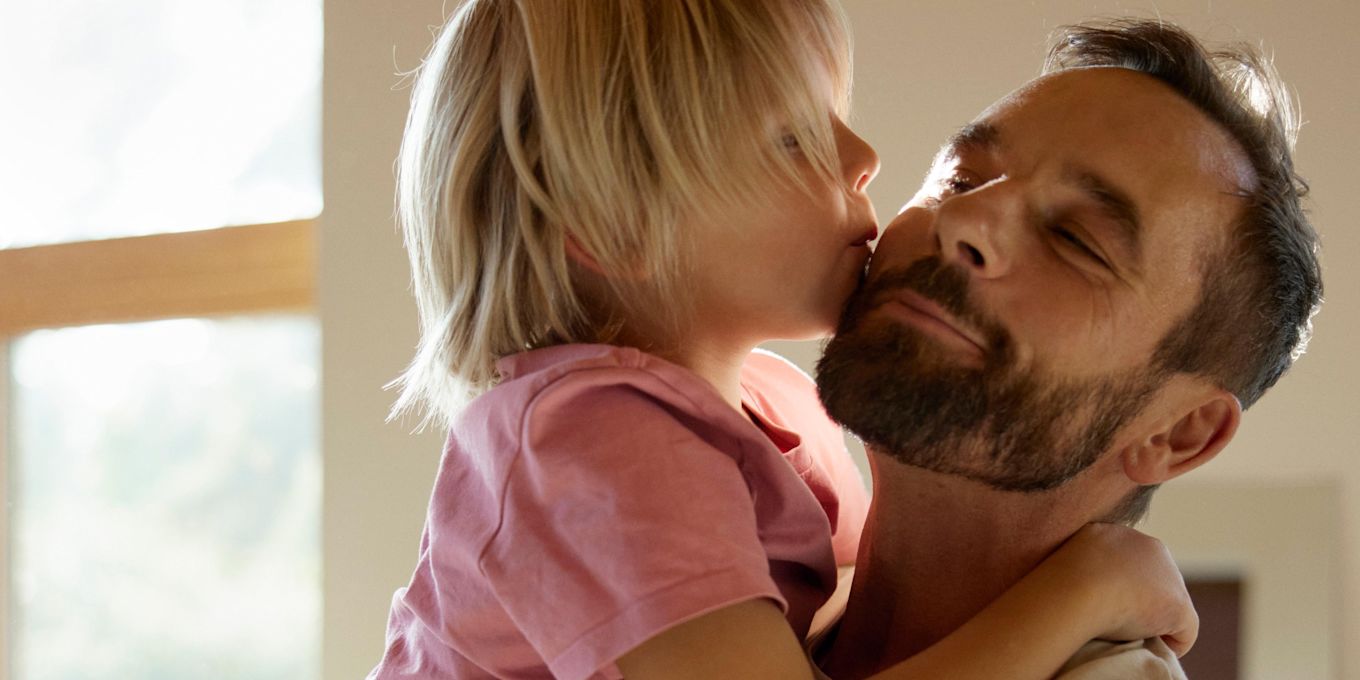 Pappa lufter upp och kramar om sitt barn, som pussar honom på kinden.