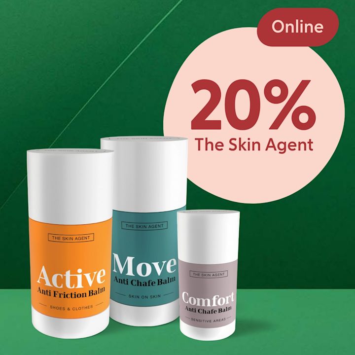 Tre cylindriska burkar med vita lock märkta "Active Anti Friction Balm", "Move Anti Chafe Balm" och "Comfort Anti Chafe Balm" stående framför grön bakgrund med en stor rosa cirkel där texten "20% The Skin Agent" och en röd etikett "Online" syns.