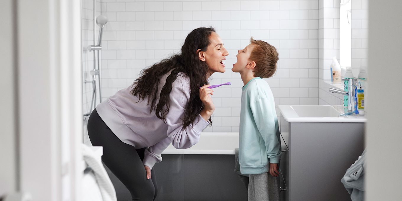 Mamma och son andas på varandra och visar sina fräscha andedräkter efter att ha borstat tänderna tillsammans.