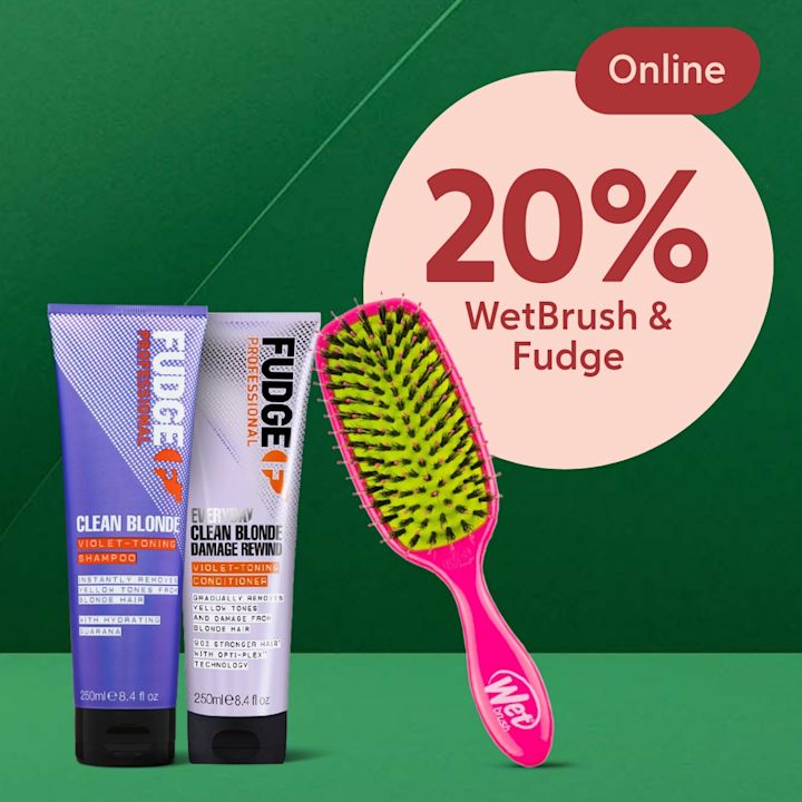 Två Fudge Clean Blonde-flaskor stående bredvid en rosa WetBrush-paddelborste med gröna borst, stor rosa cirkel visar "20% WetBrush & Fudge" och en röd oval med texten "Online".