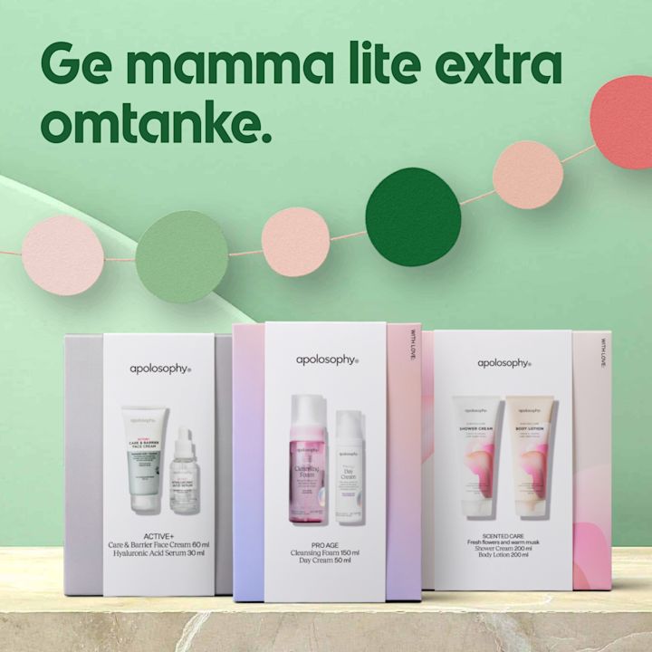 Tre vita presentförpackningar med apolosophy hudvårdsprodukter stående på ett marmorbord, framför en mintgrön bakgrund med texten "Ge mamma lite extra omtanke" och hängande cirkelflaggor i rosa och grönt.
