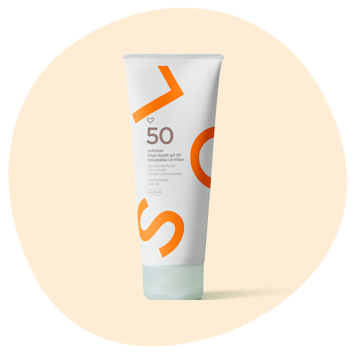 Solkrämstub med texten "50 solotion, högt skydd spf 50, fotostabila UV-filter", vit förpackning med orange detaljer mot beige bakgrund.